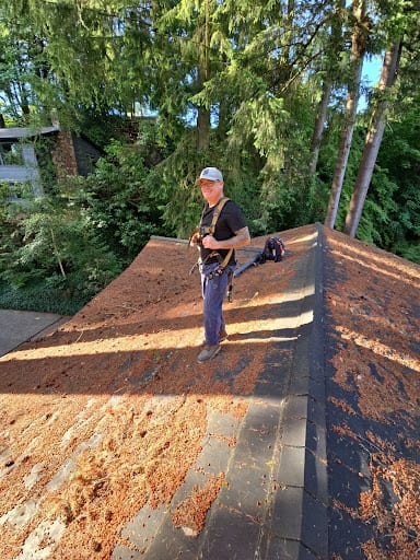 RoofWorks technician inspecting a roof to check drainage and clear debris